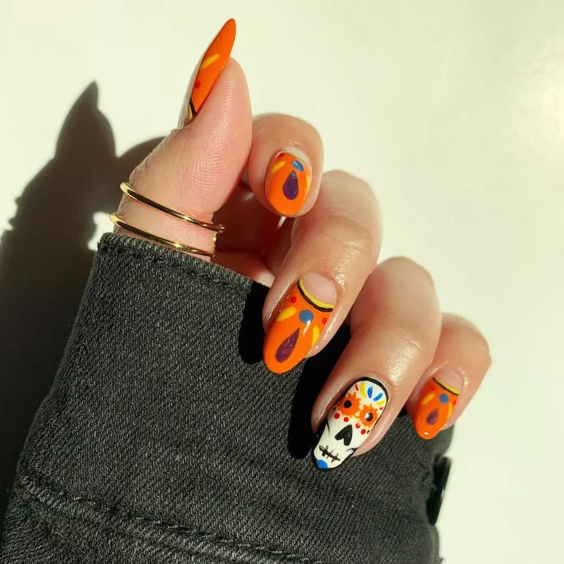 Dia de los Muertos orange patterned manicure with sugar skull accent nail