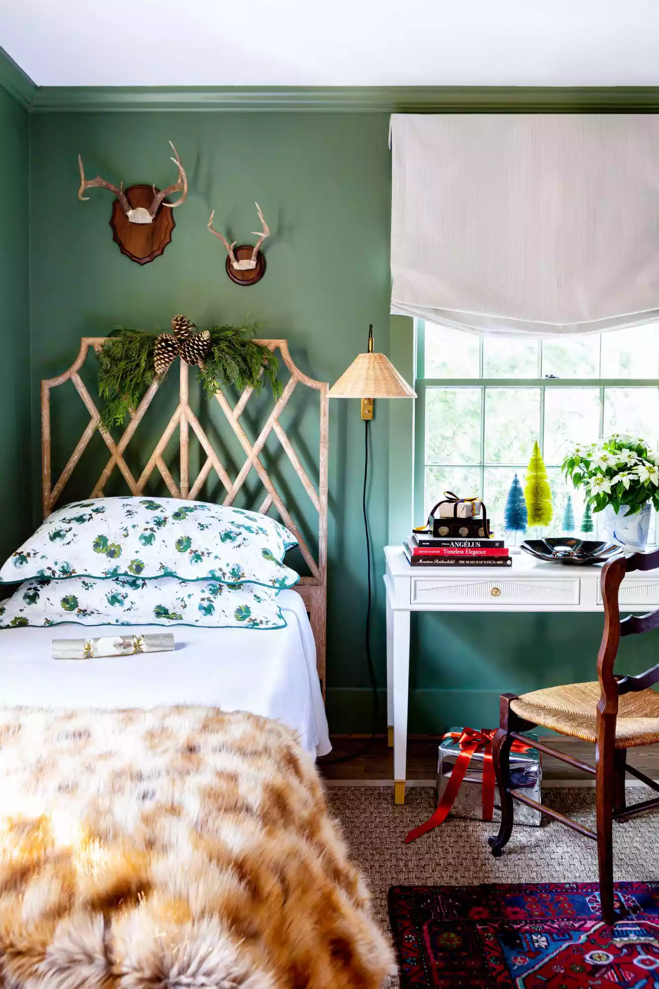 Green guest room with twin beds decorated for Christmas with greenery and bottle brush trees.