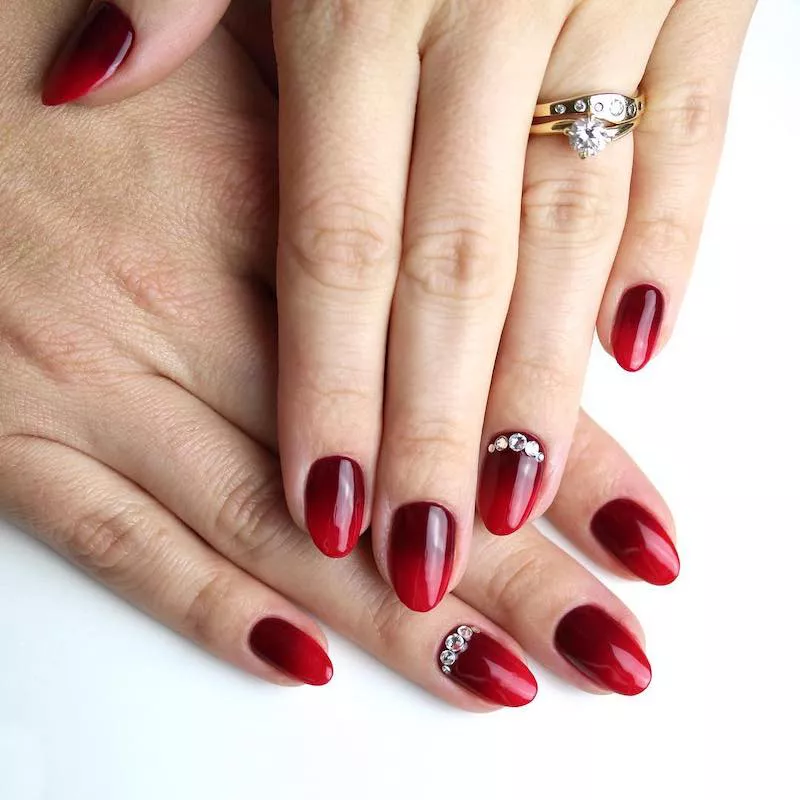 Oxblood.to bright red ombre manicure with jeweled accent nail