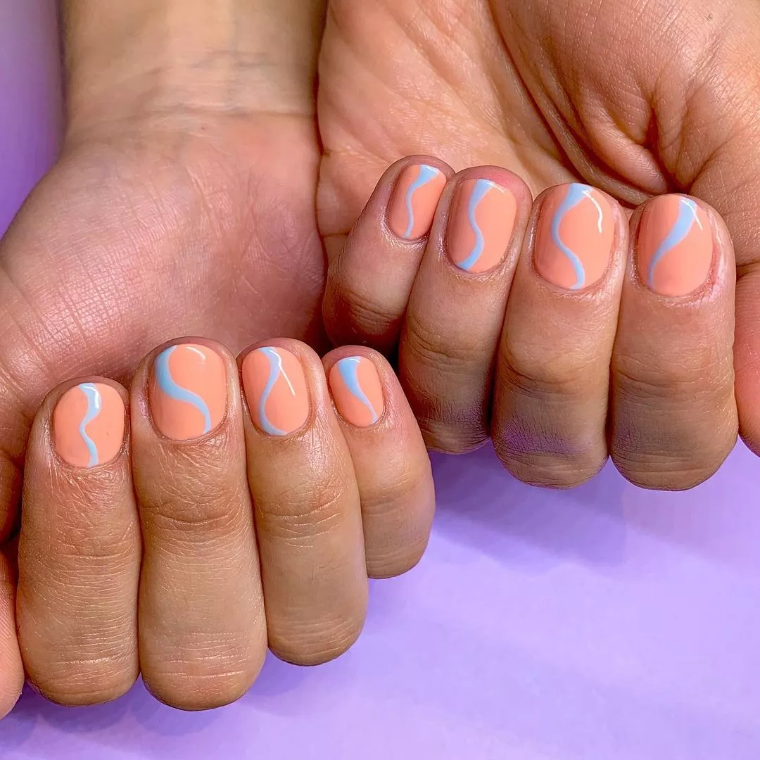 Peach nails with blue wavy lines at the center of each nail