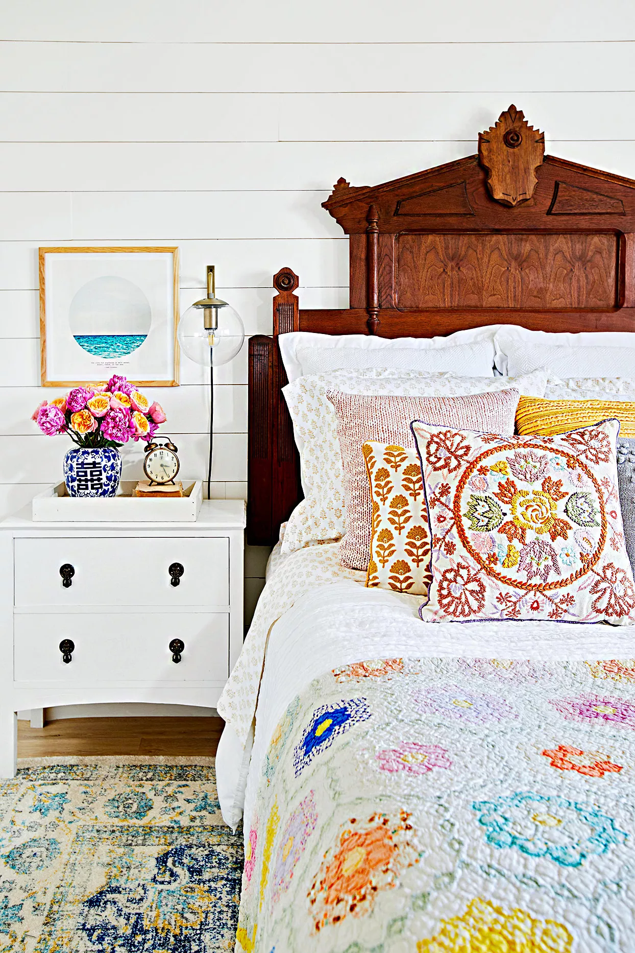 Bed with colorful quilt and embroidered pillows