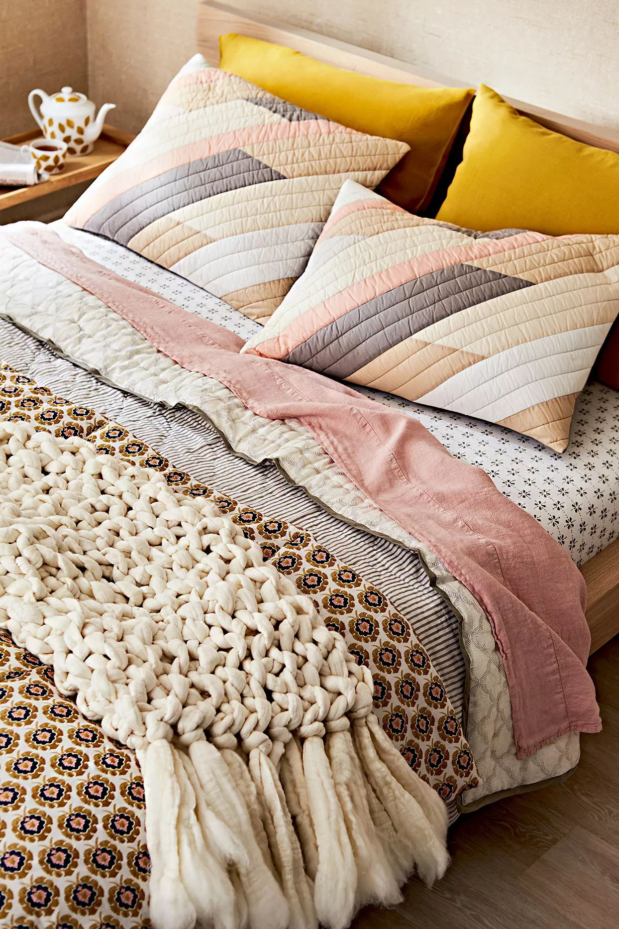 Bed with knit throw blanket and striped pillows