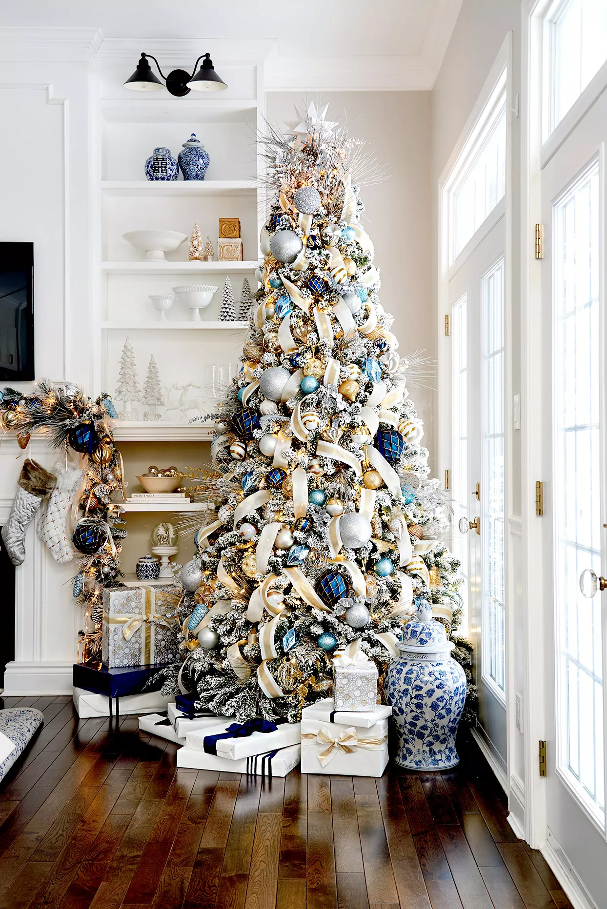 Christmas tree in corner of room with gold, blue, and white theme