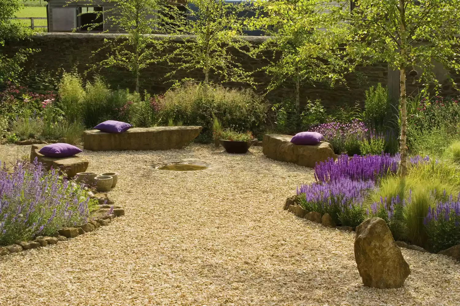 Lavender in gravel garden with rock seating and purple pillows