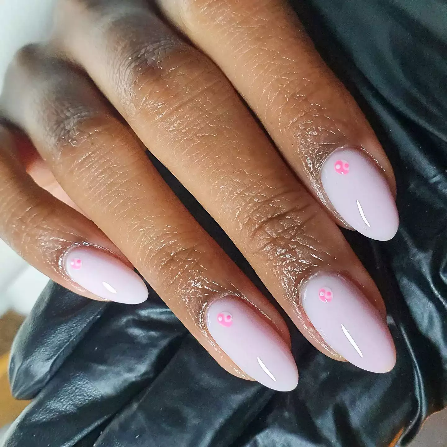 Pink nails with small yin and yang stickers near the cuticles
